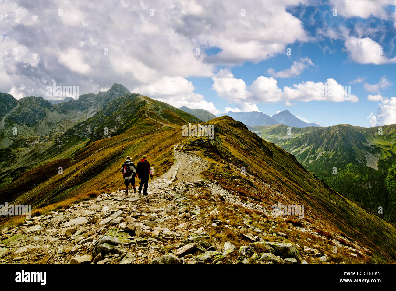 Two Man Hiking Up Steep Hill with Backpacks and Rocky Mountain View Stock Photo