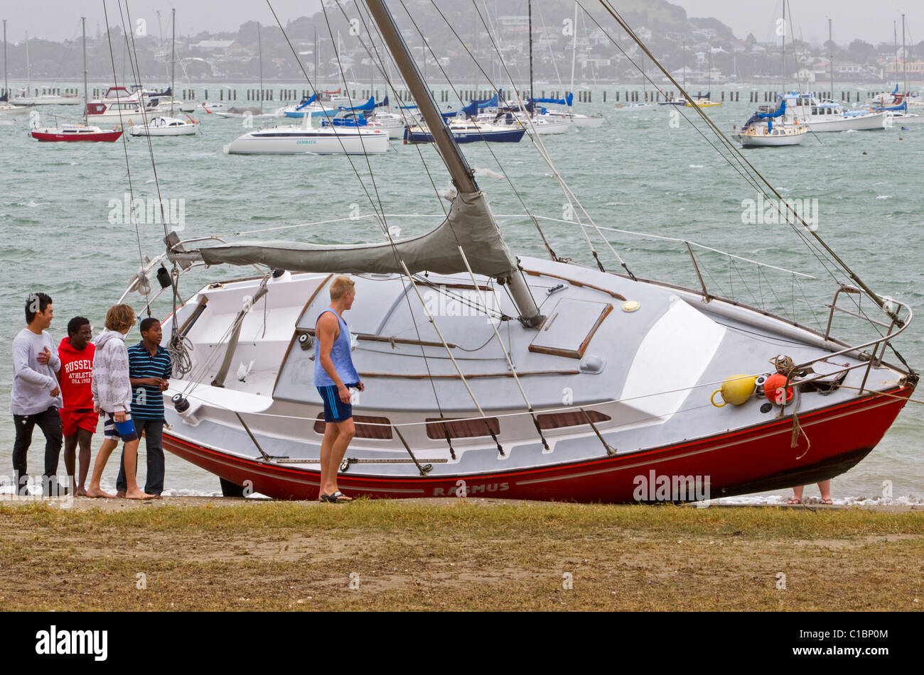 A yacht is beached after heavy rain and strong winds, Mission Bay, Auckland, New Zealand Stock Photo