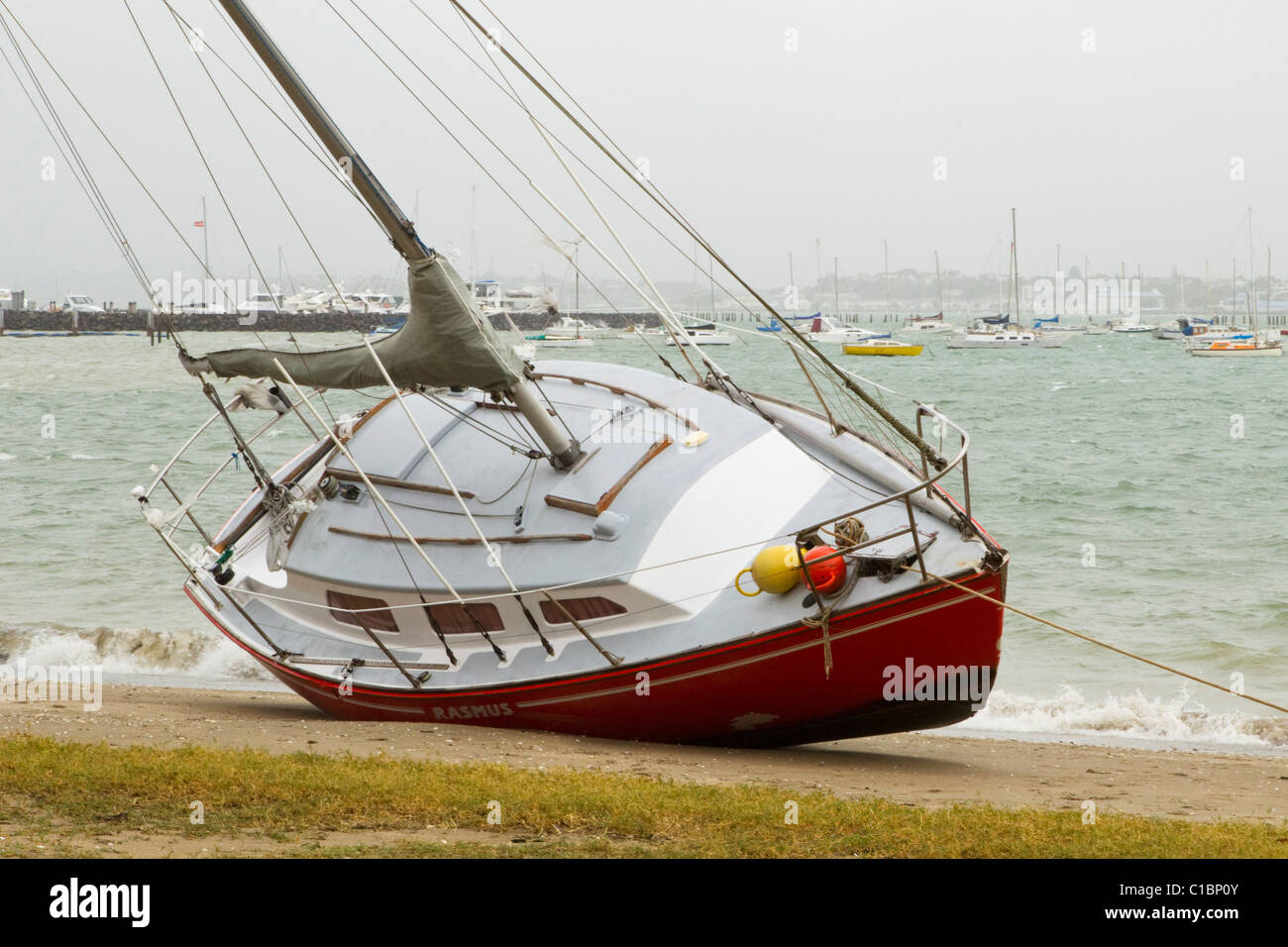 A yacht is beached after heavy rain and strong winds, Mission Bay, Auckland, New Zealand Stock Photo