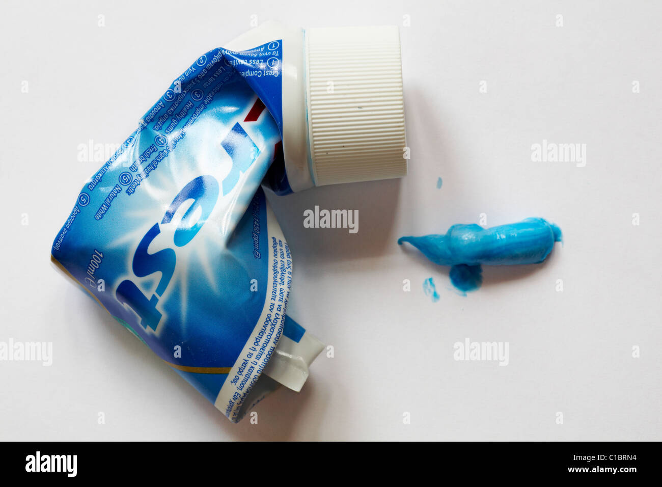 Old tube of Crest toothpaste with toothpaste blob isolated on white
