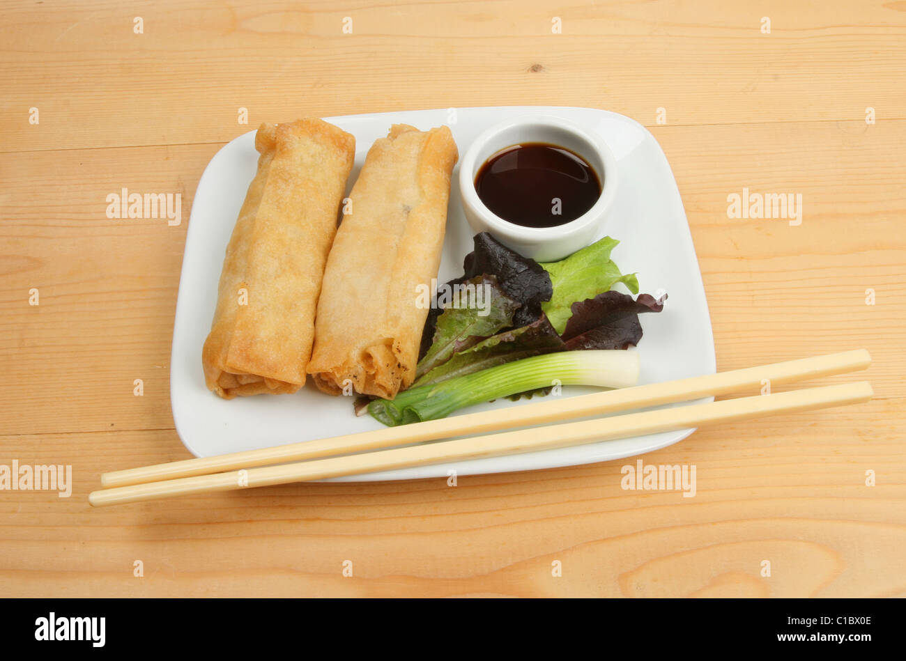 Chinese pancake rolls, salad garnish and chopsticks on a plate Stock Photo
