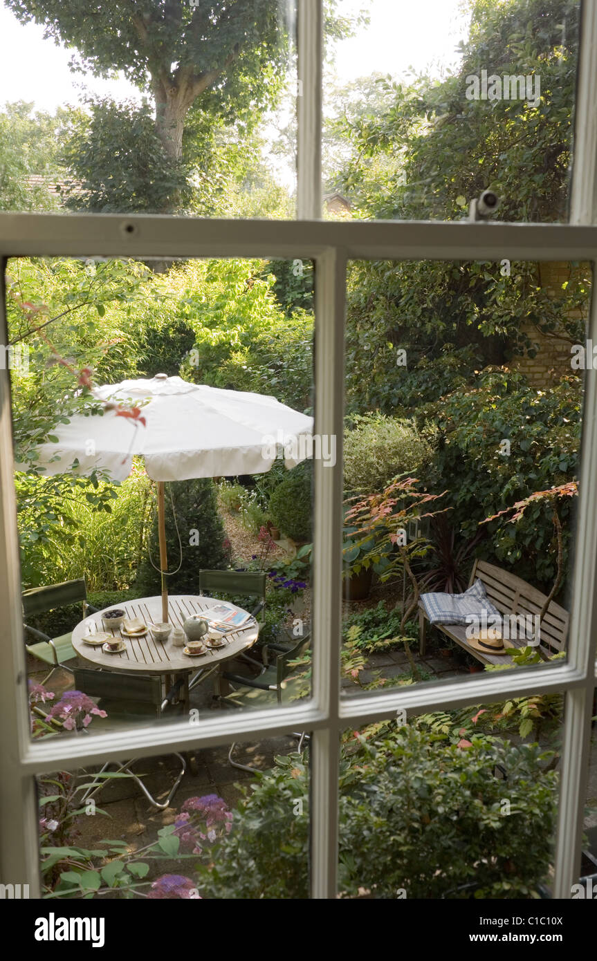 View through window down to garden patio with parasol and bench Stock Photo