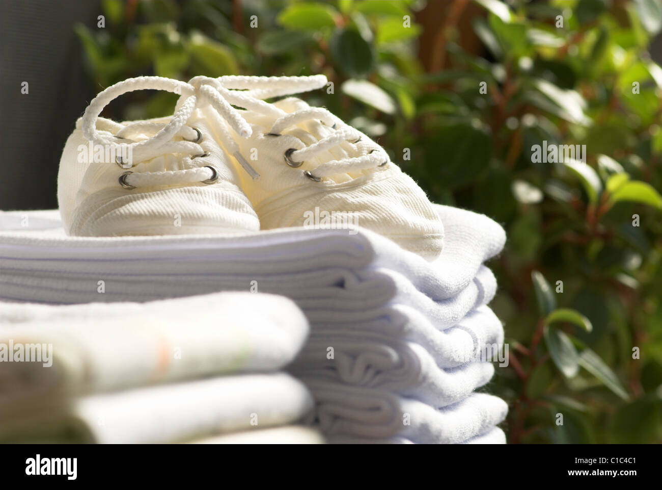 Stack of swaddling bands with baby's bootees on floral background Stock