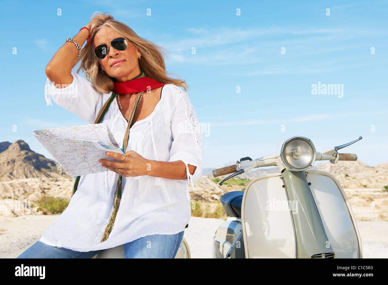 Woman sitting on motorbike with map Stock Photo