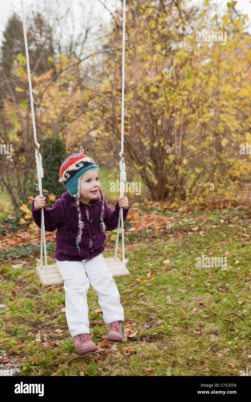 Little girl on a swing in the garden Stock Photo - Alamy