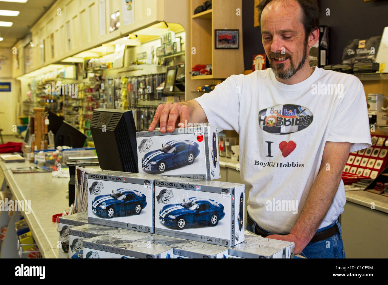 Hobby shop store with retail employee displaying model cars Stock Photo