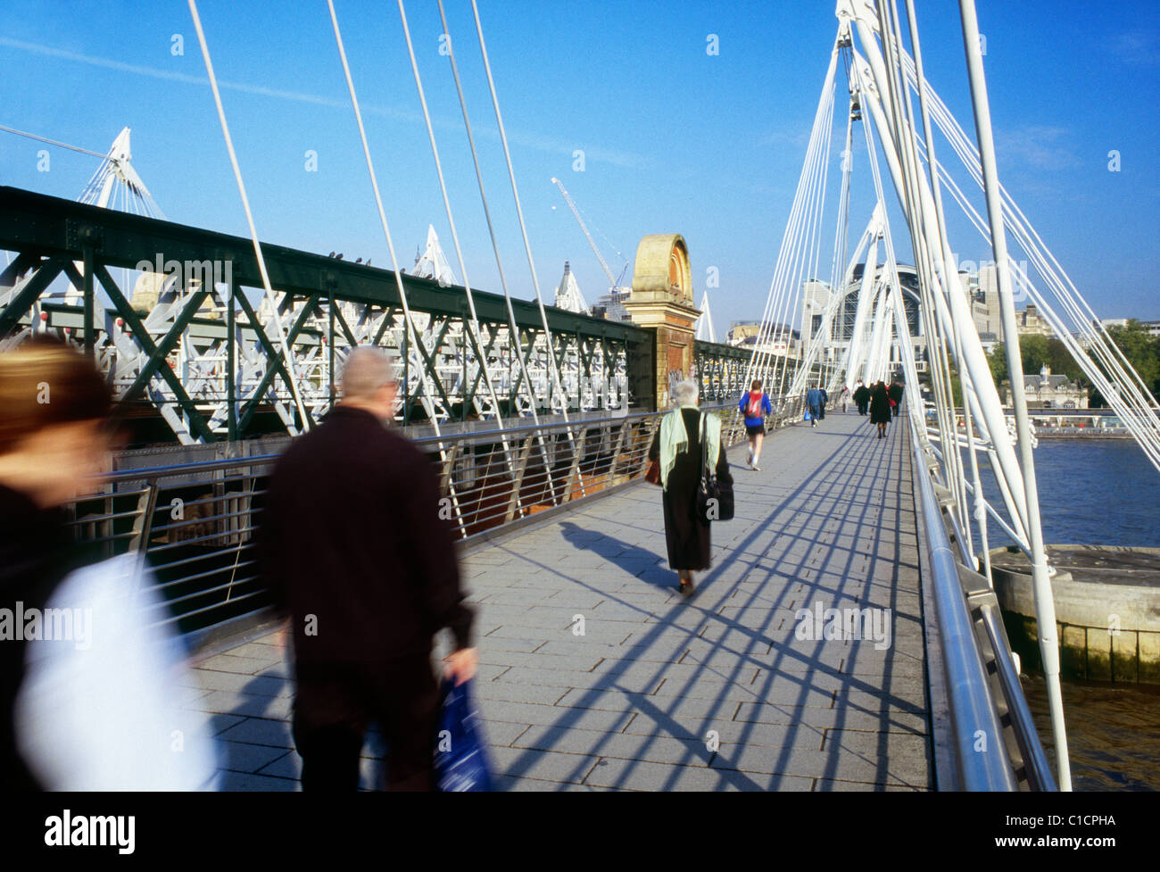 Commuters walking across Hungerford Bridge over the River Thames
