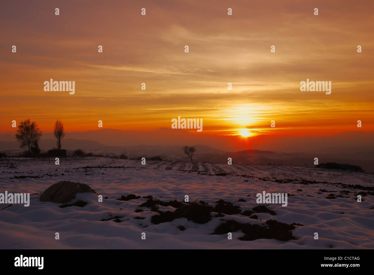 Beautiful winter sunset with snow over cultivated land Stock Photo