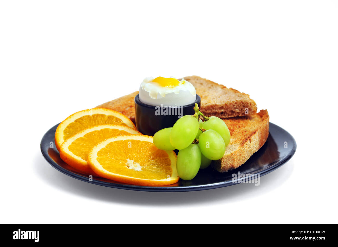 Perfect healthy breakfast: hard boiled egg, slices of oranges, green grapes and multigrain toasted bread. Stock Photo