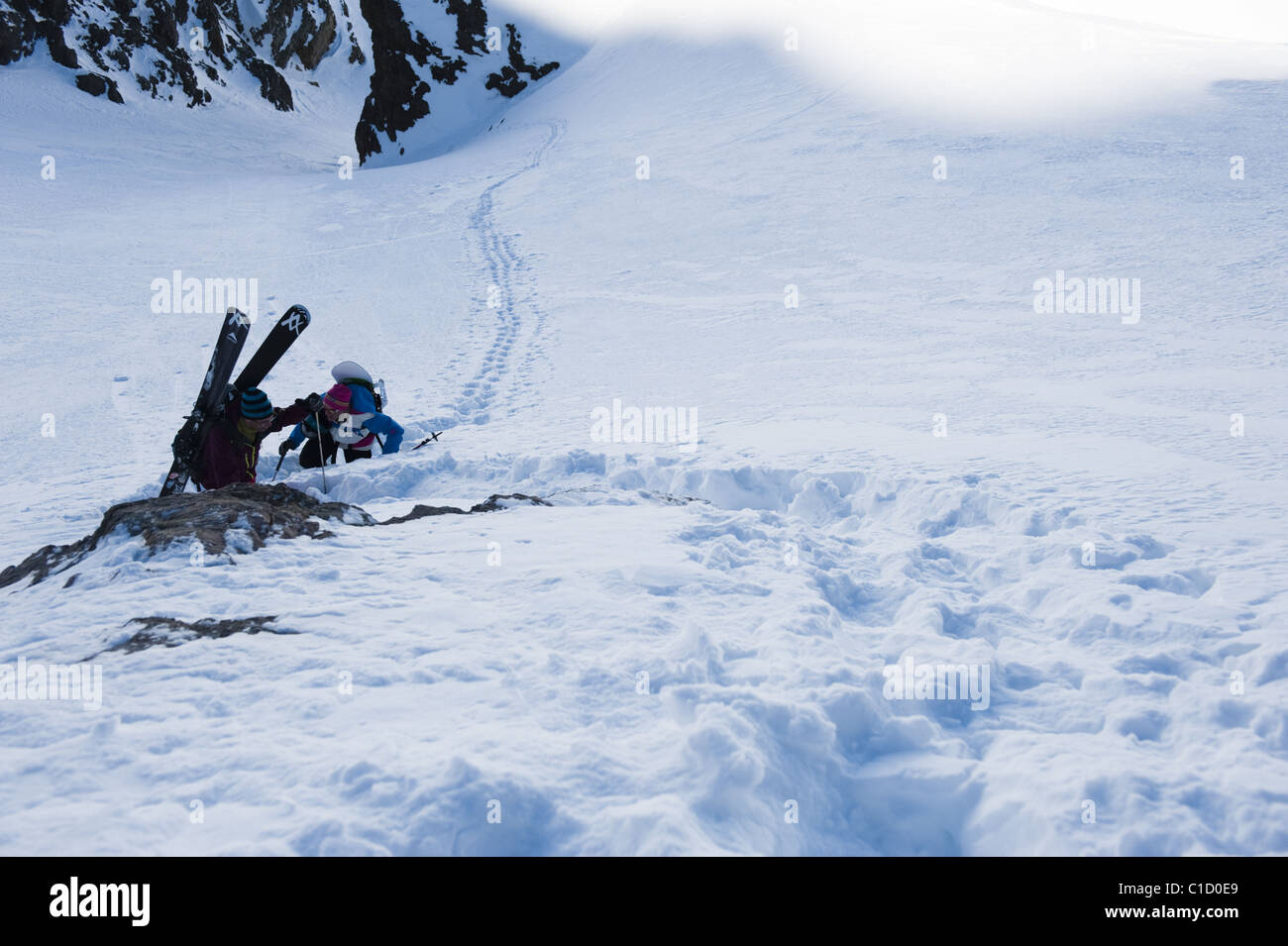 A free skier and a snowboarder climbing up a snowy mountain side near La Grave, France Stock Photo