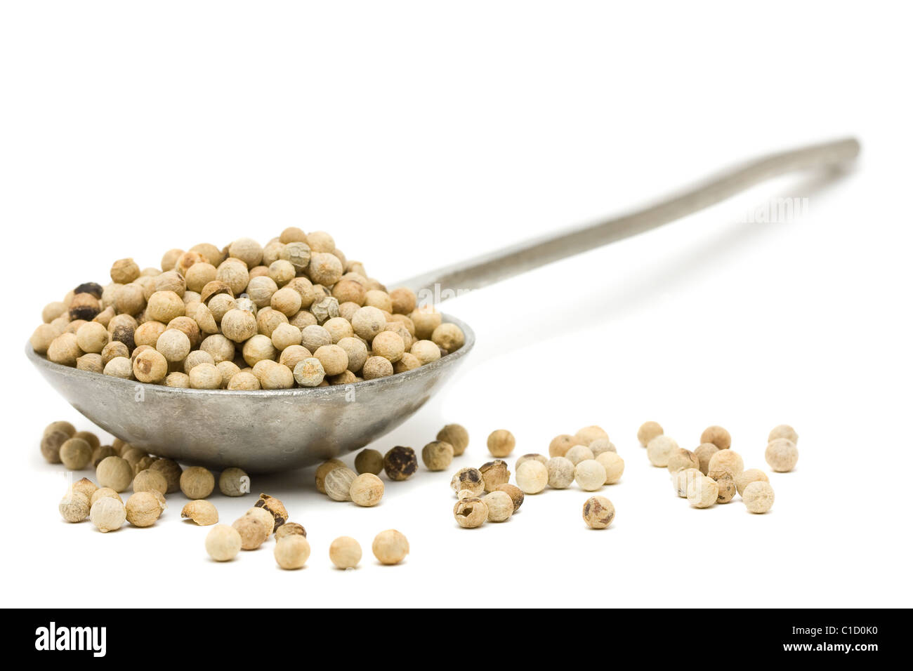 White peppercorns on metal spoon over white background Stock Photo