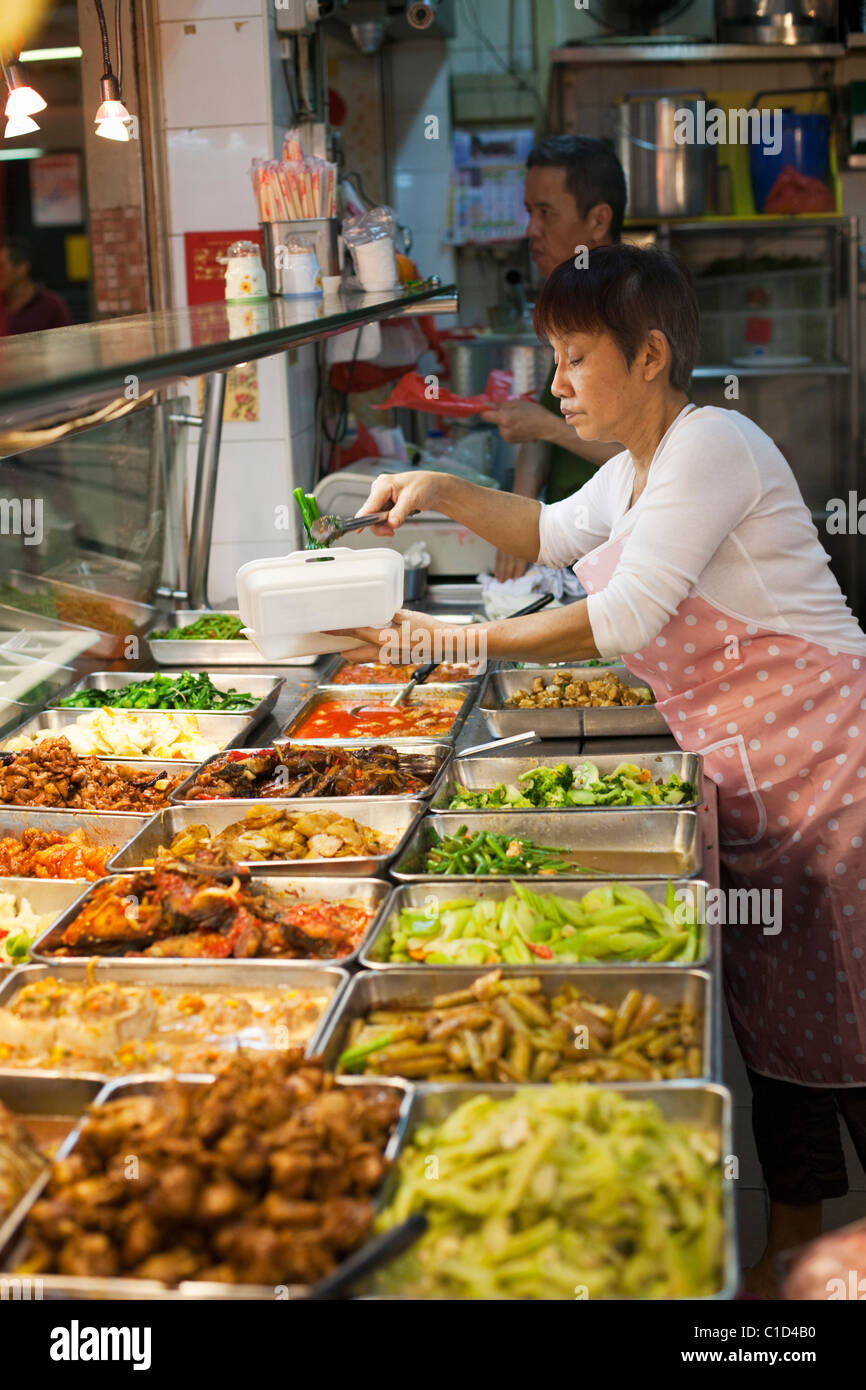 Woman serving from the many dishes at a hawker stall at People's Park Complex.  Chinatown, Singapore Stock Photo