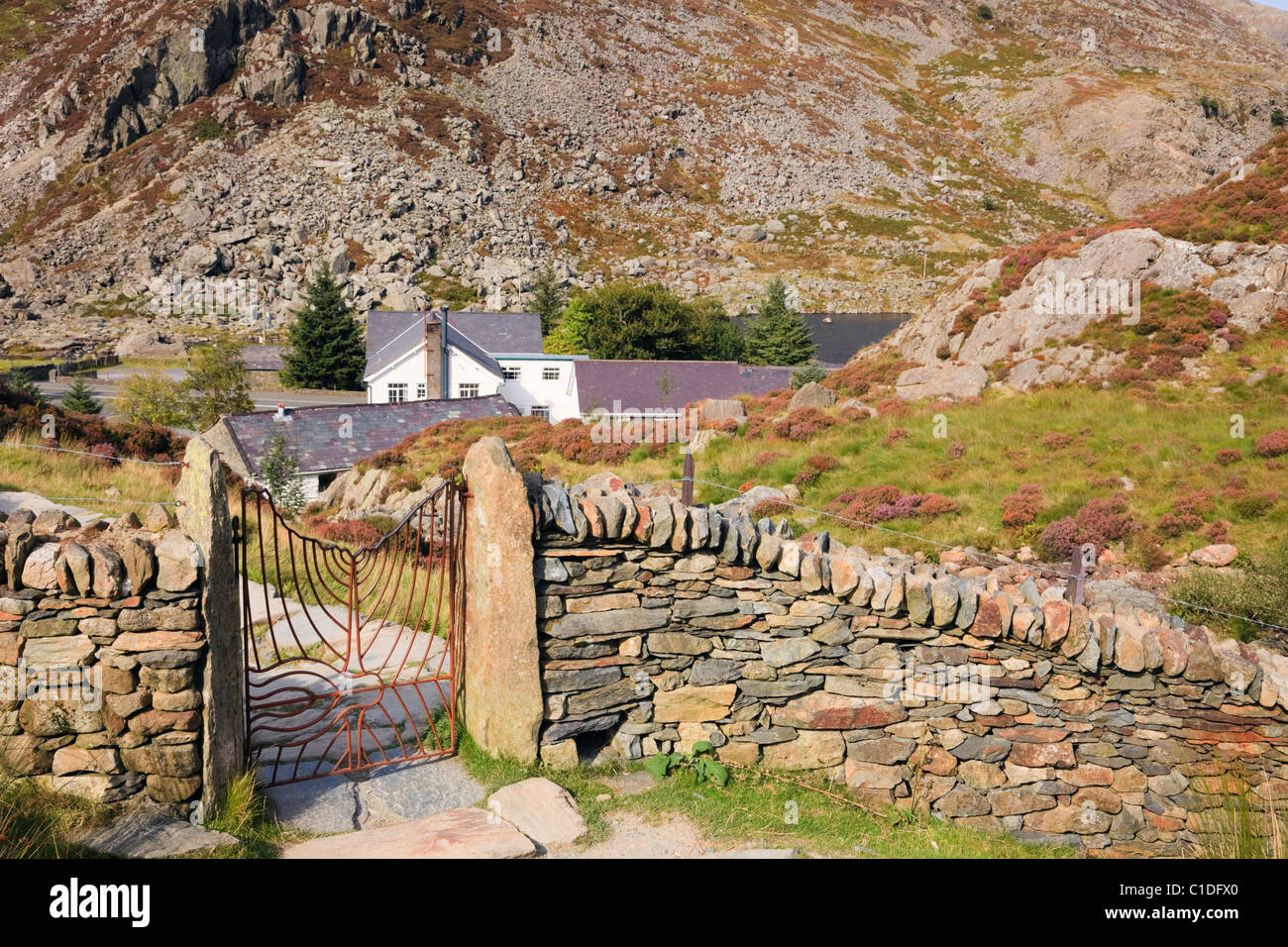 Ogwen Valley, Snowdonia, North Wales, UK. Footpath from Cwm Idwal with Ogwen Cottage Outdoor Pursuits Centre beyond drystone wall Stock Photo