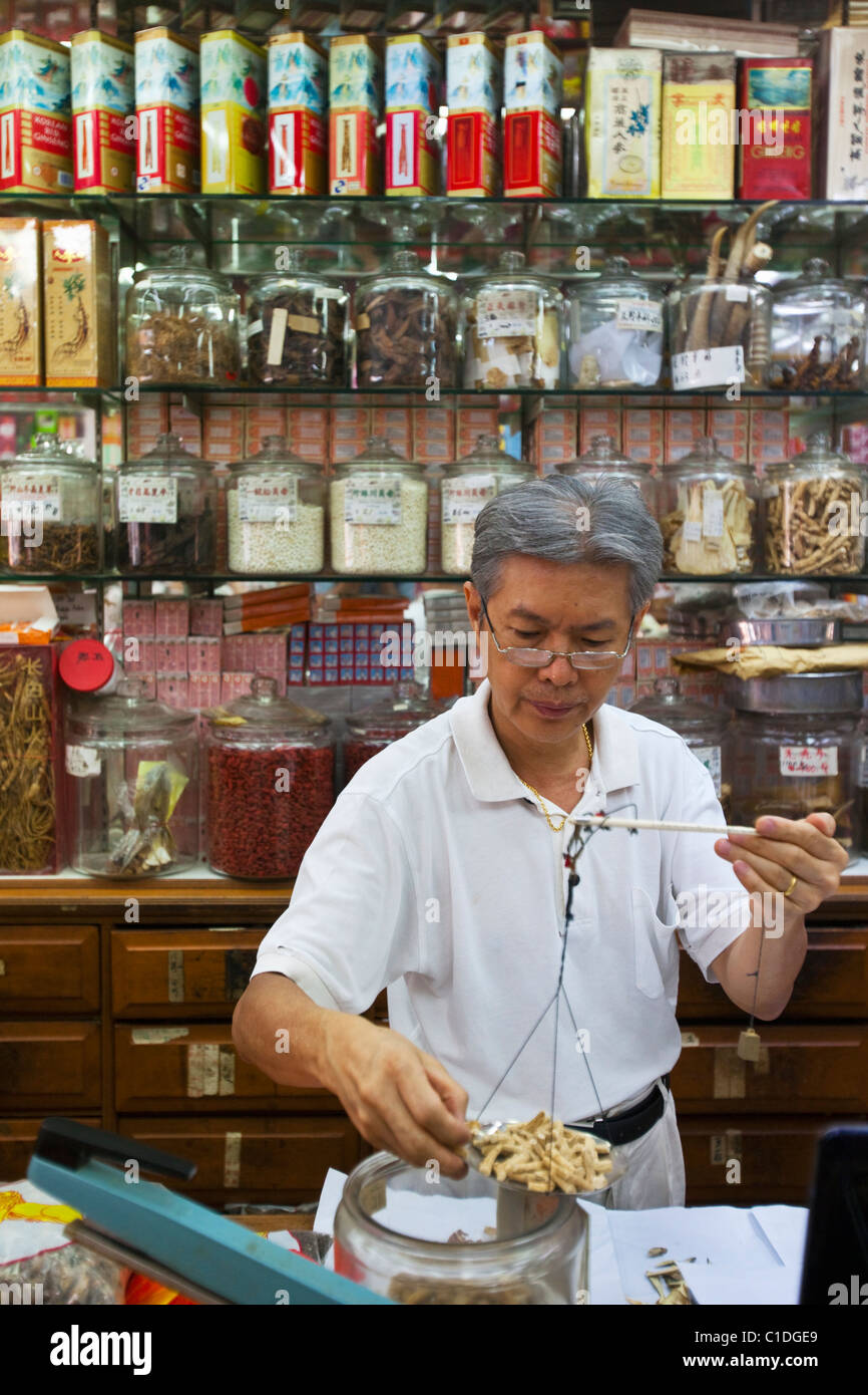 A shopkeeper weighs out ingredients in a traditional chinese medicine