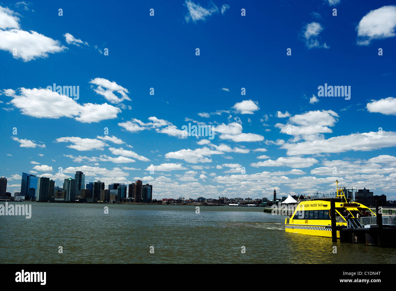 New York City Skyline with a yellow water taxi under a deep blue sky ...