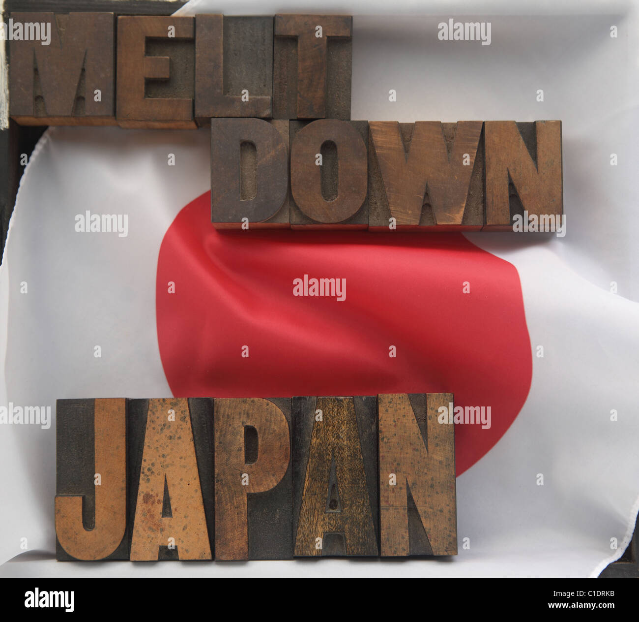 the words Japan and meltdown in old wood type on a Japanese flag Stock Photo