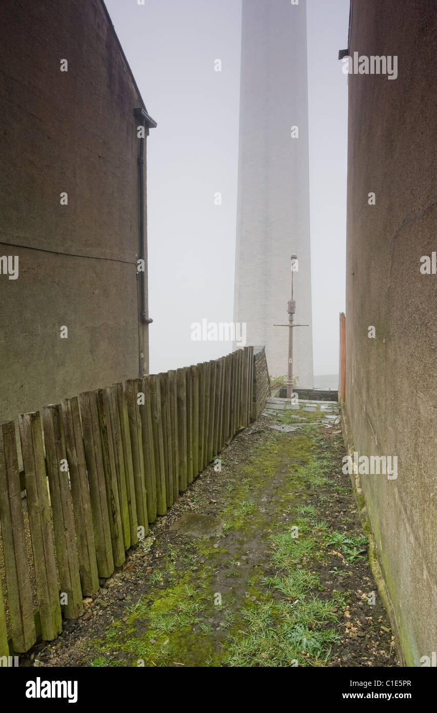 passageway between terraced houses with gaslamp and mill chimney in background Stock Photo