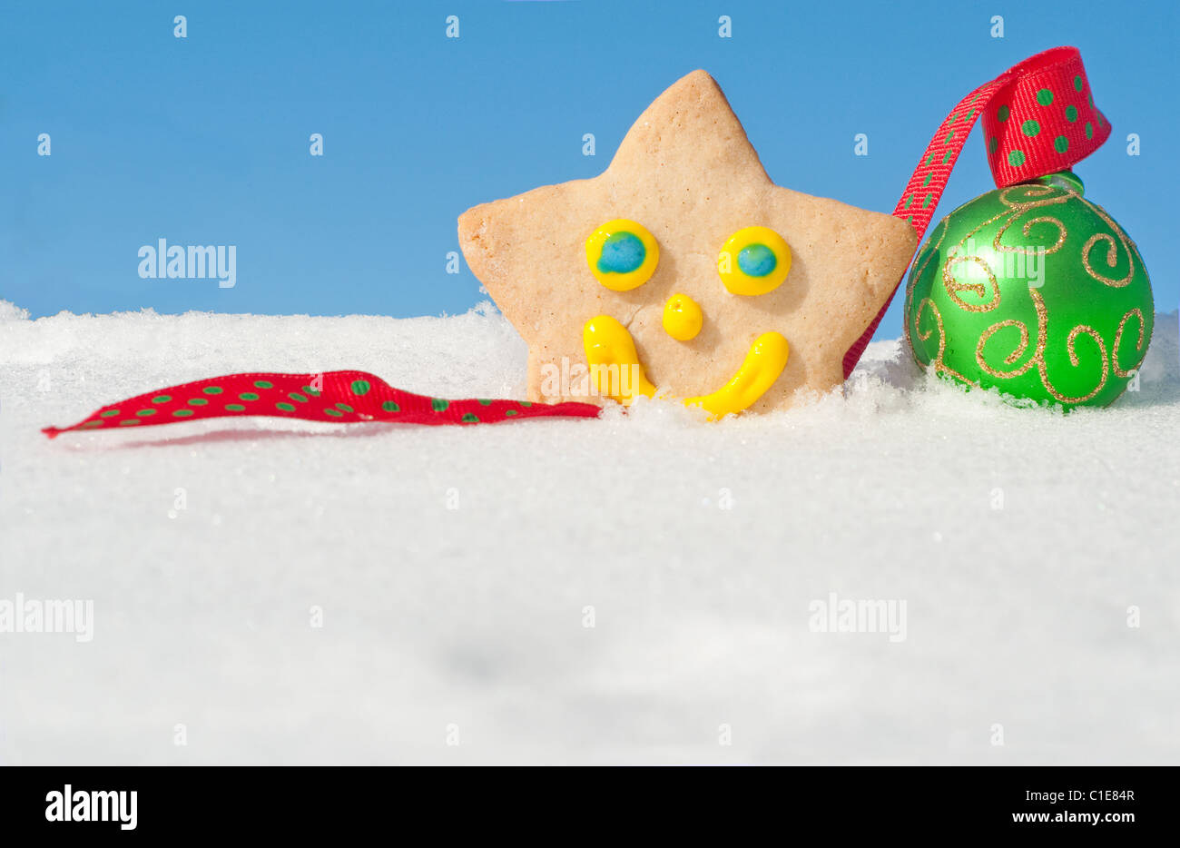 A delightful Christmas cookie on snow with a green Christmas bauble, with copy space Stock Photo