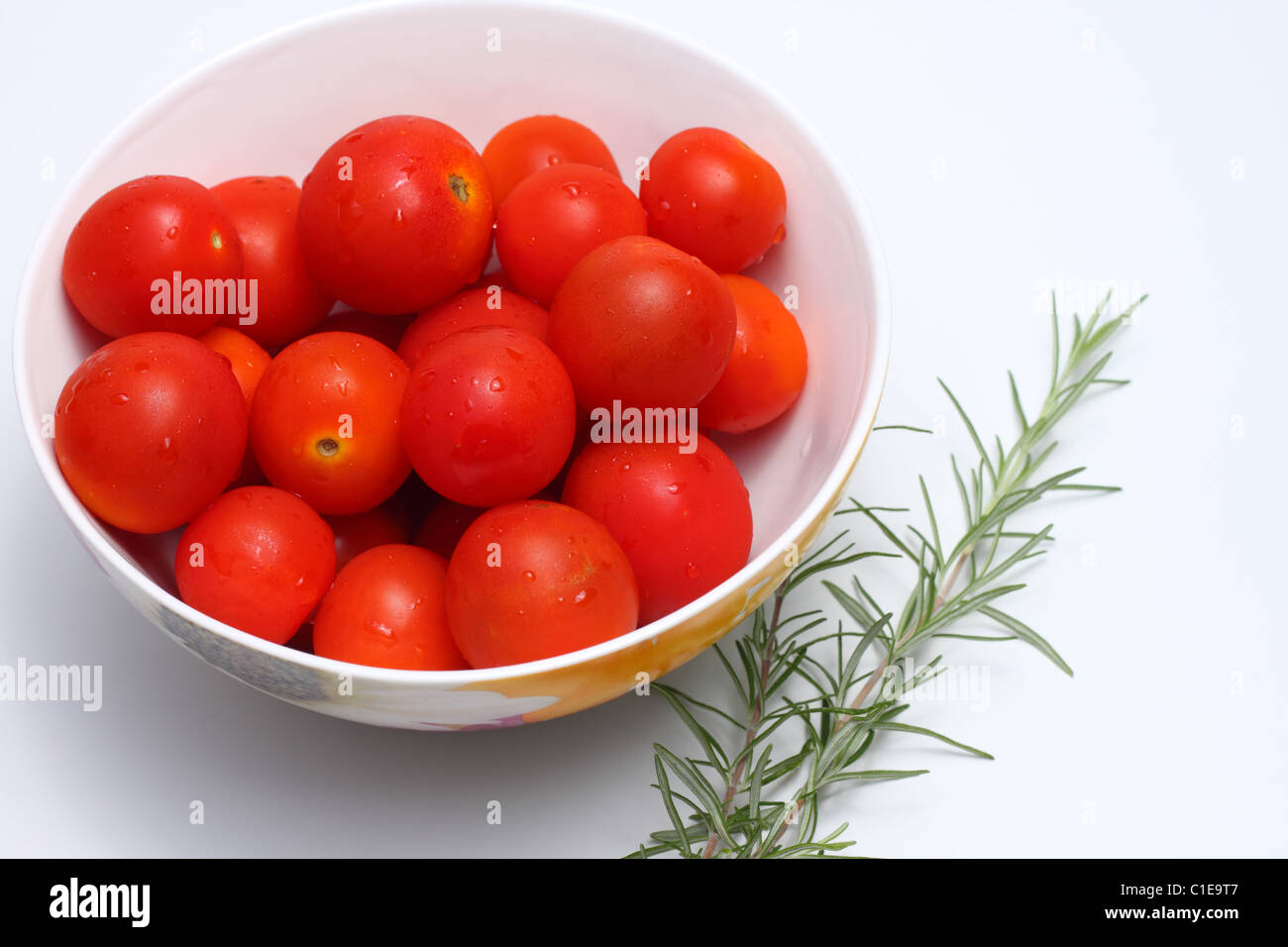 Bowl of red cherry tomatoes and some rosemary Stock Photo - Alamy