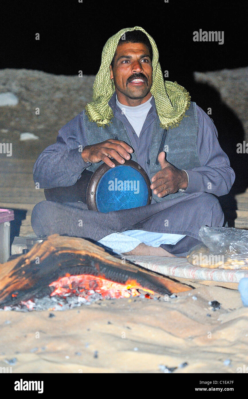 Egyptian musician playing tam tam drum near a bonfire during an overnight stay in the White Desert national park, Egypt Stock Photo