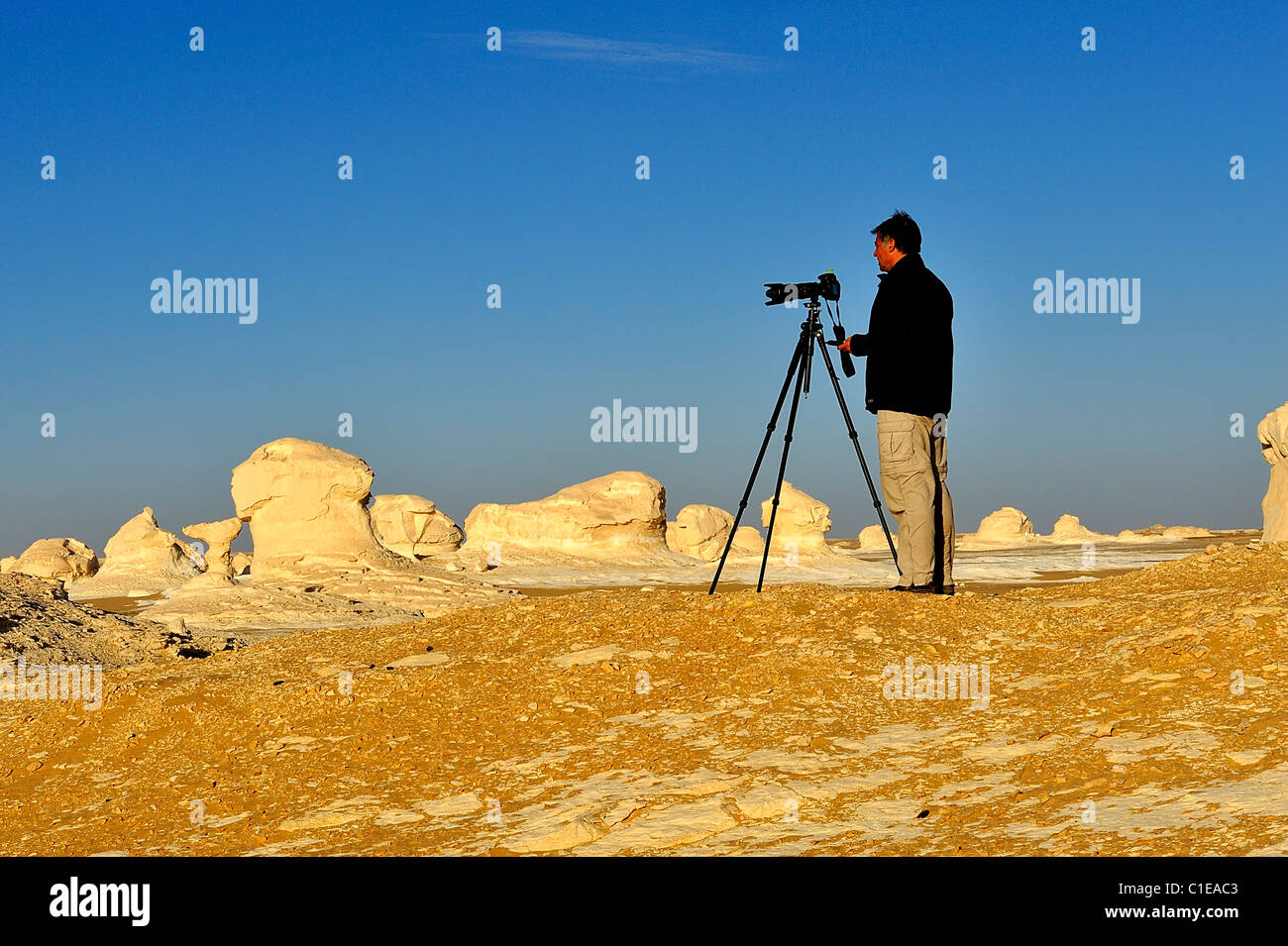 Man photographer shooting sand dunes with a camera on a tripod in the ...