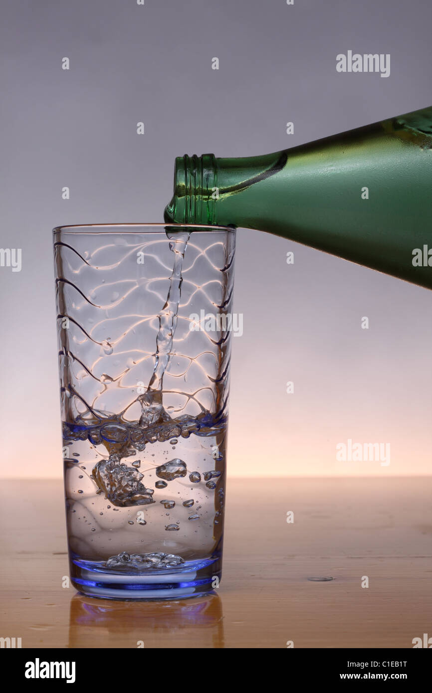 Pouring cold water from green bottle into blue glass Stock Photo Alamy