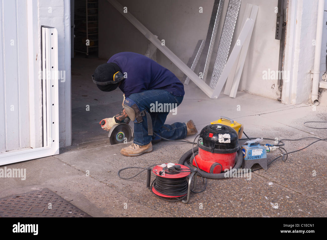 A builder using an angle grinder to cut through a concrete floor in the Uk  Stock Photo - Alamy