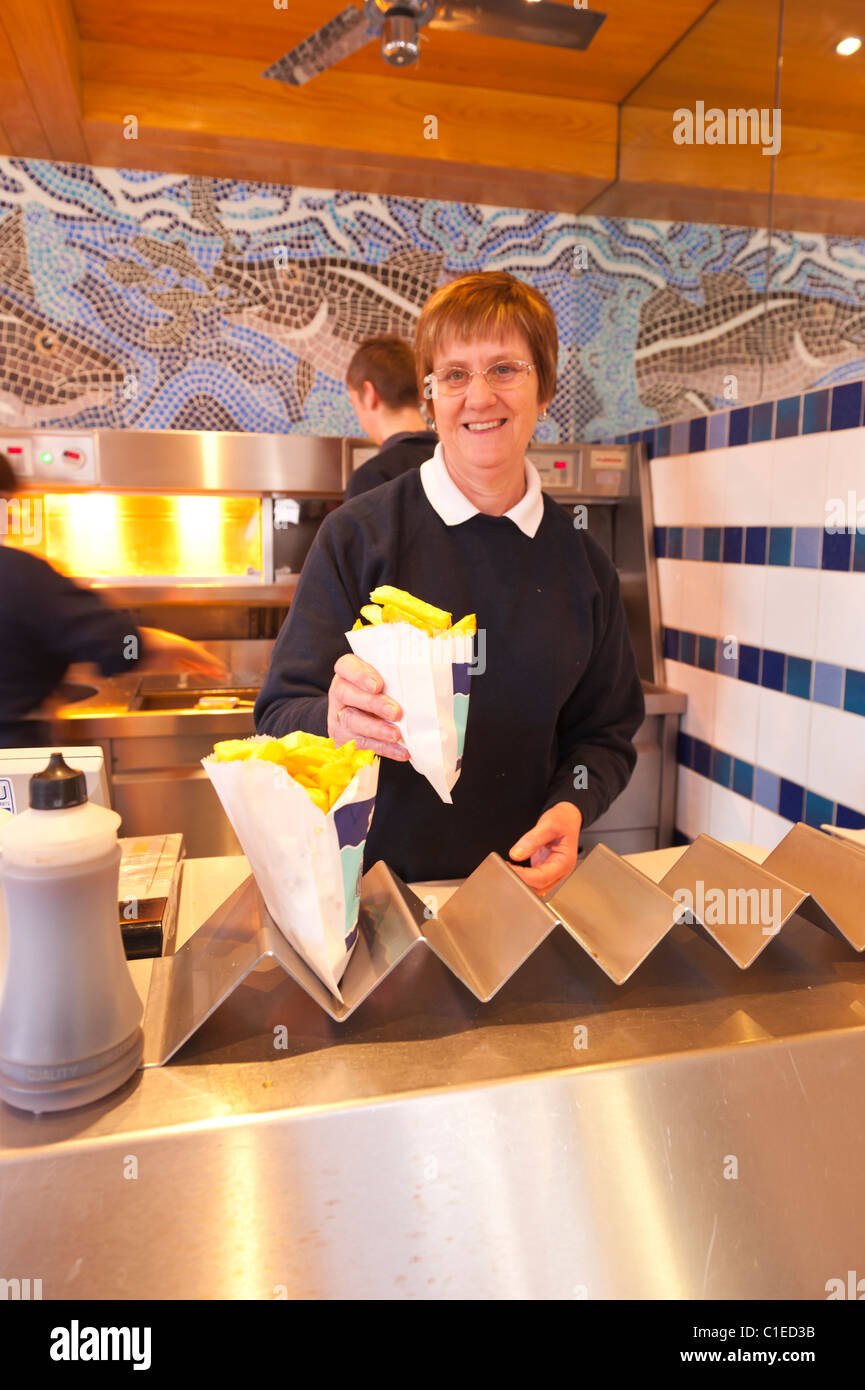 Inside a British fish and chip shop with focus on the bag of chips in Aldeburgh , Suffolk , England , Britain , Uk Stock Photo
