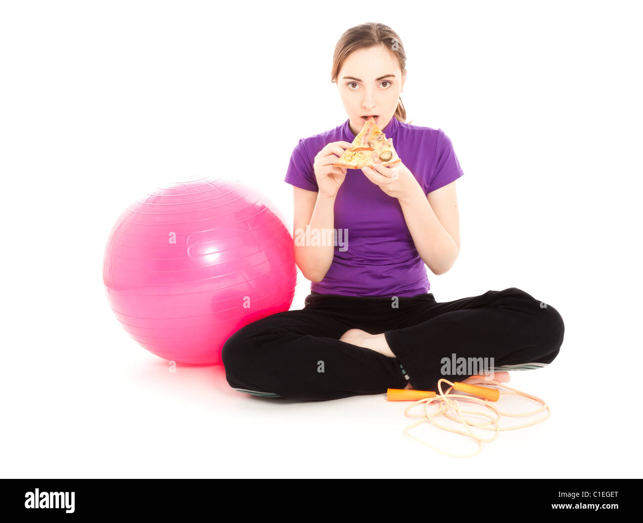 Woman with a slice of pizza, pink gymnastics ball and jump rope Stock Photo