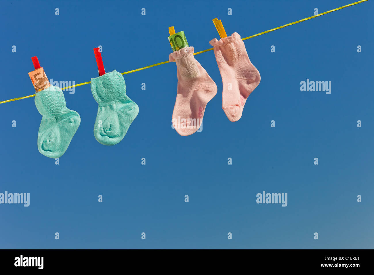 Baby socks on clothesline with euro banknotes. Blue sky Stock Photo Alamy