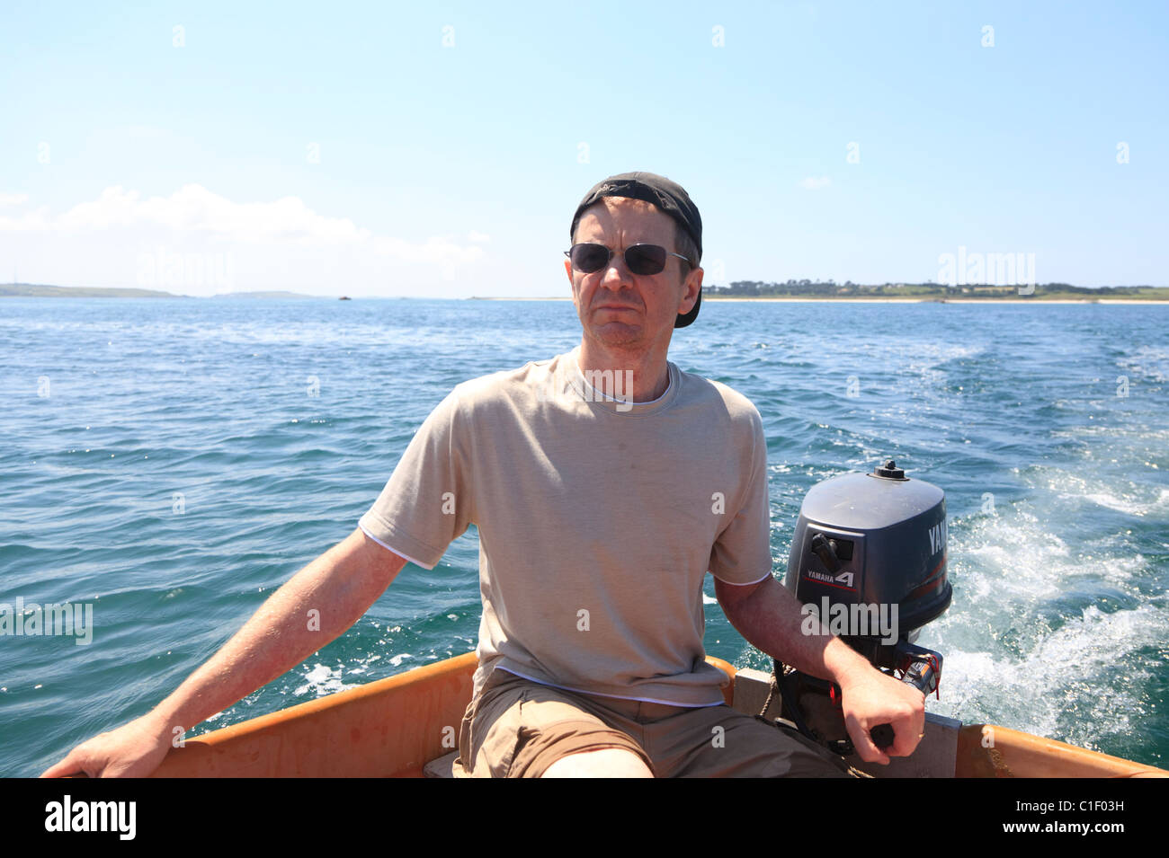 Man steering small boat from outboard motor Stock Photo