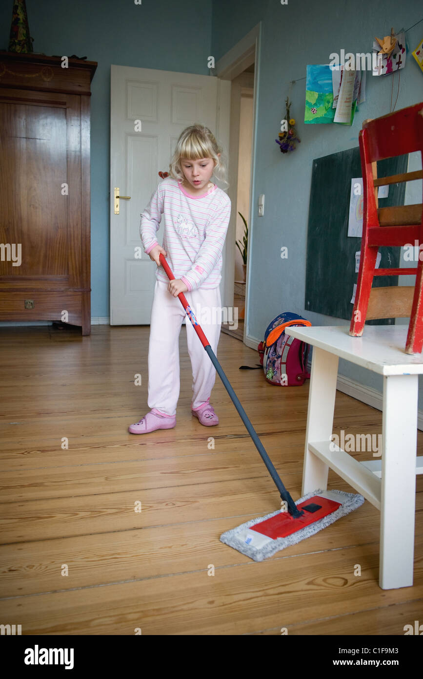 A little girl doing household chores in her room Stock Photo