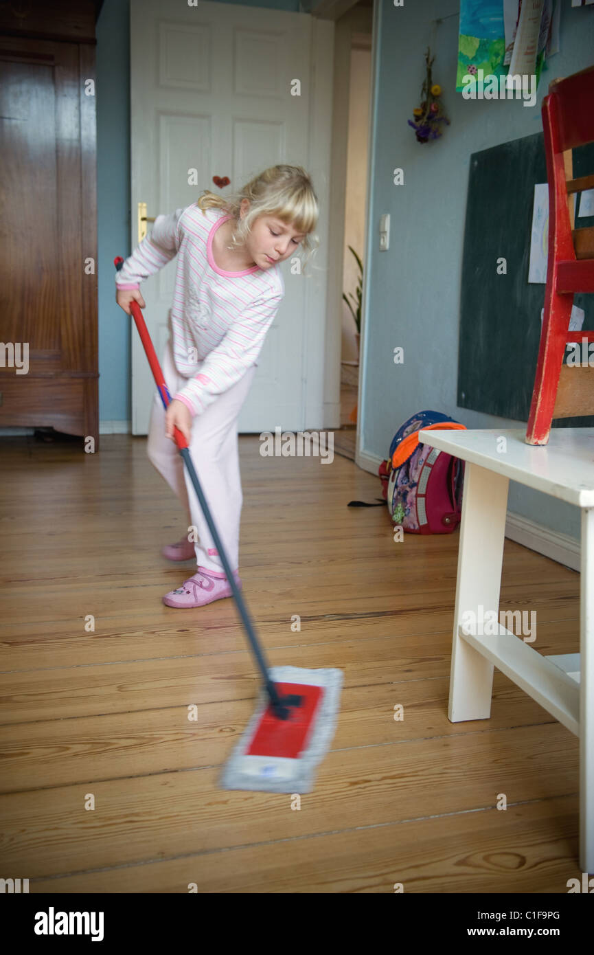 A little girl doing household chores in her room Stock Photo