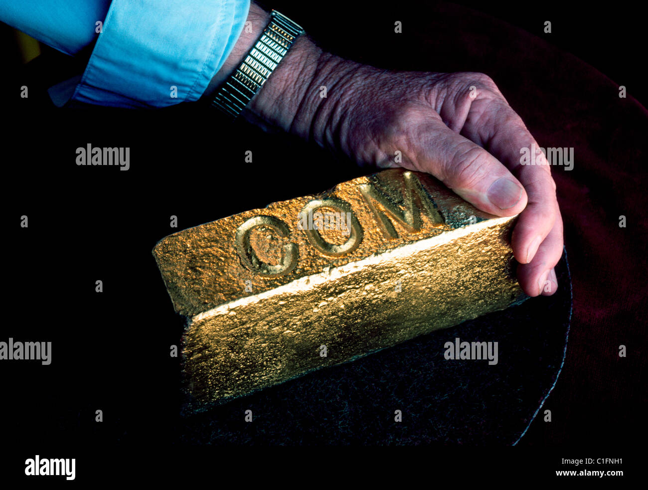 A man's hand grasps an ingot of gold molded and stamped by the Chamber of Mines (COM) at a Johannesburg gold mine in South Africa. Stock Photo