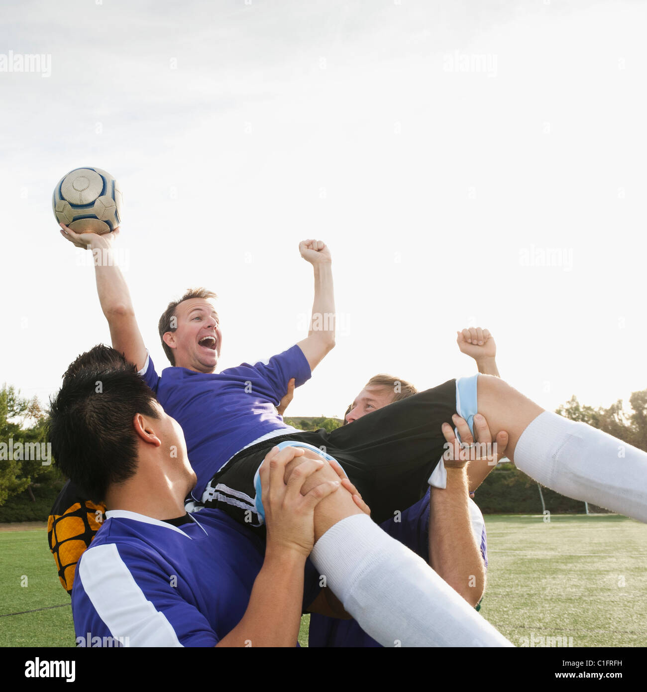 Soccer players lifting teammate and cheering Stock Photo