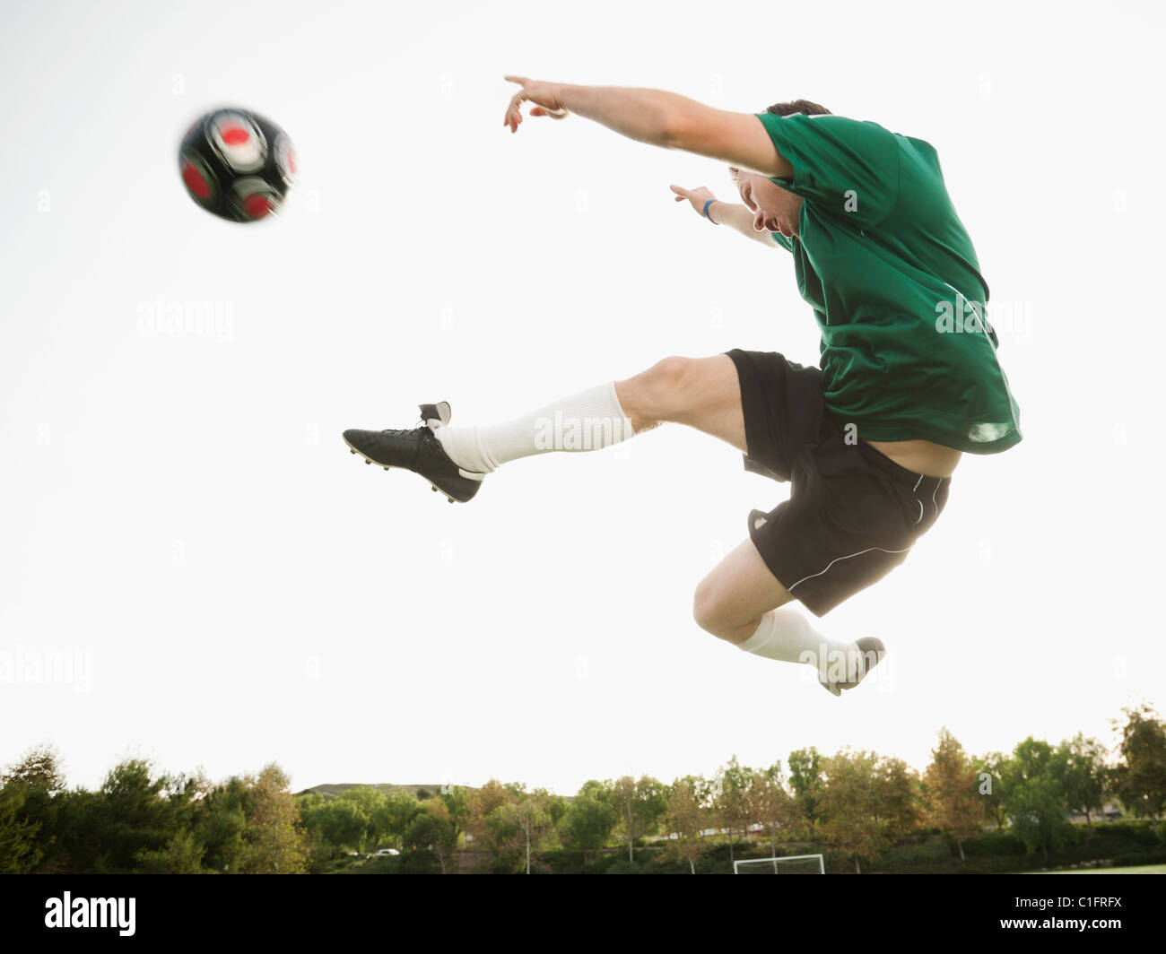 Caucasian soccer player in mid-air kicking soccer ball Stock Photo