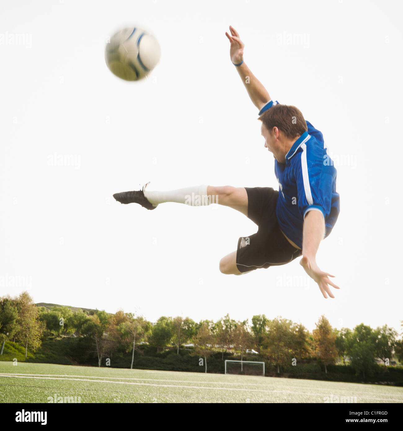 Caucasian soccer player in mid-air kicking soccer ball Stock Photo