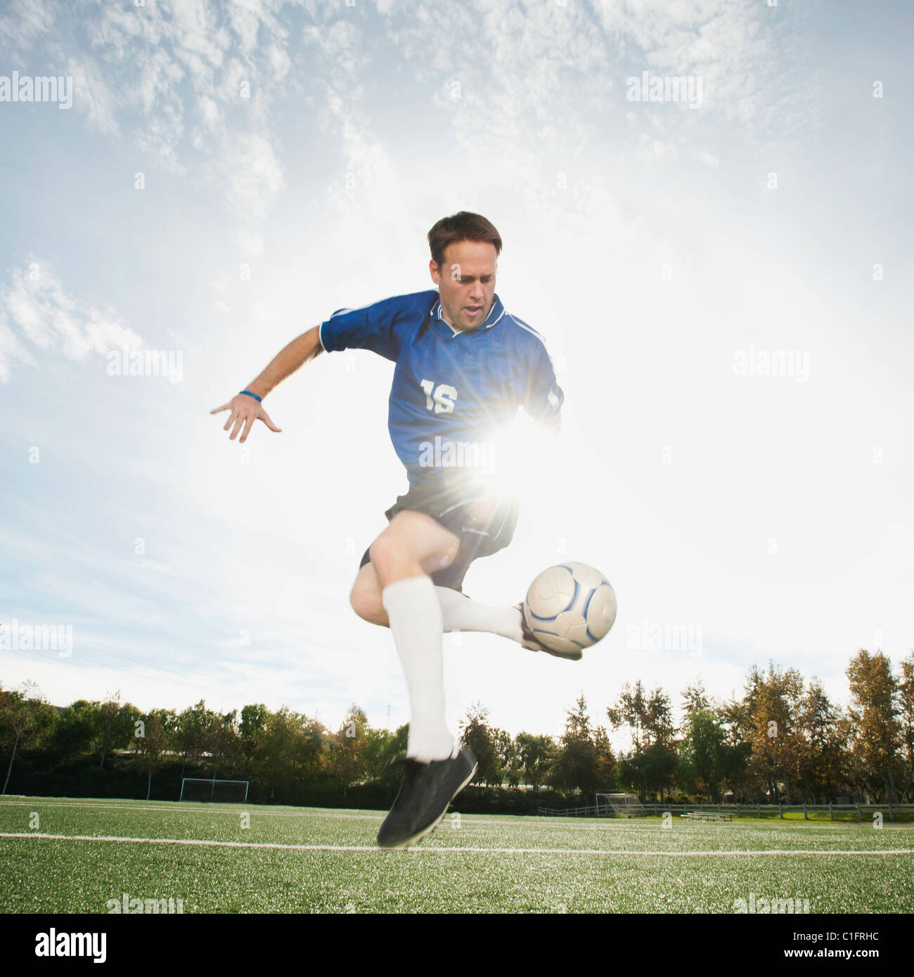 Caucasian soccer player kicking soccer ball Stock Photo