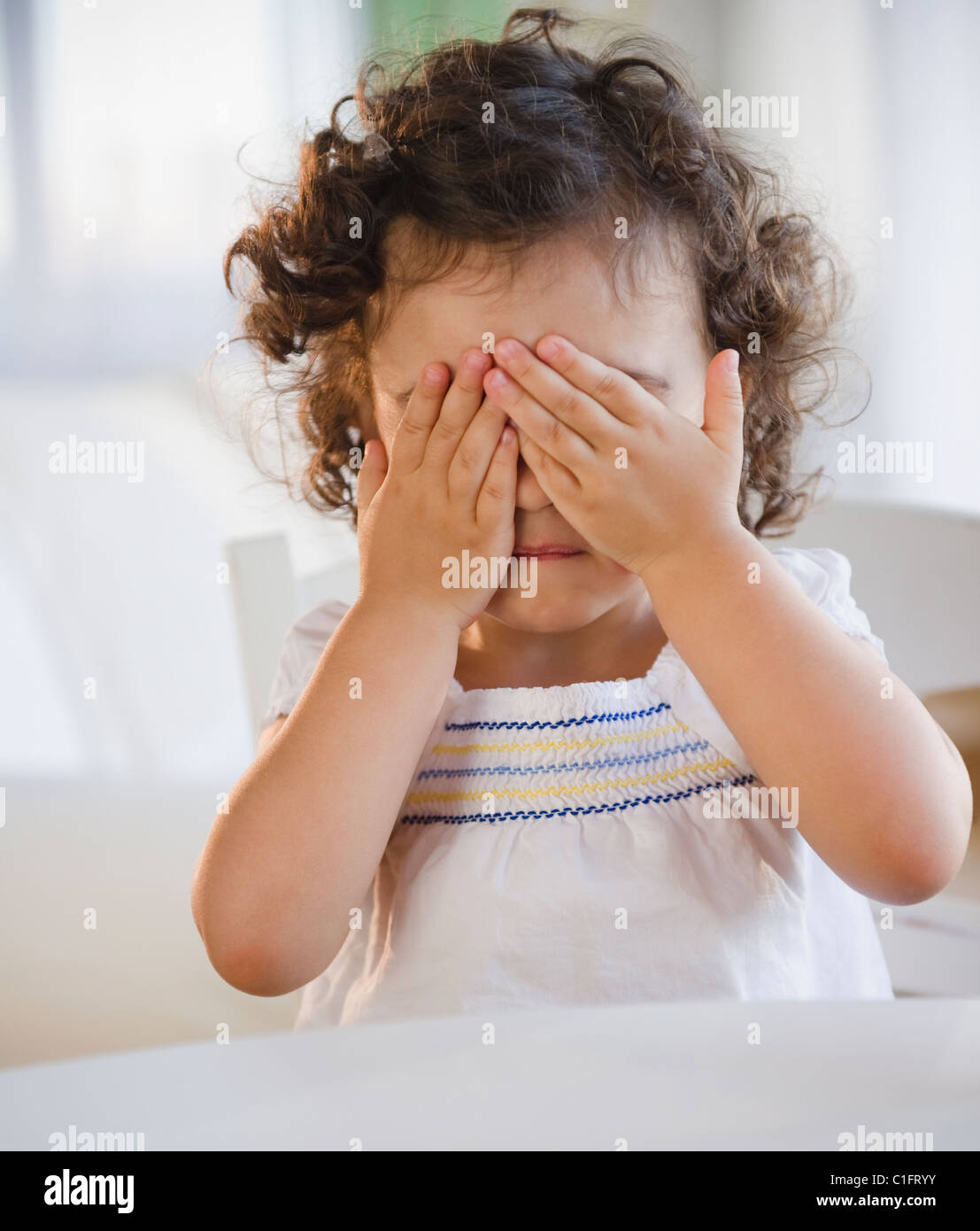 Mixed race girl covering her eyes Stock Photo