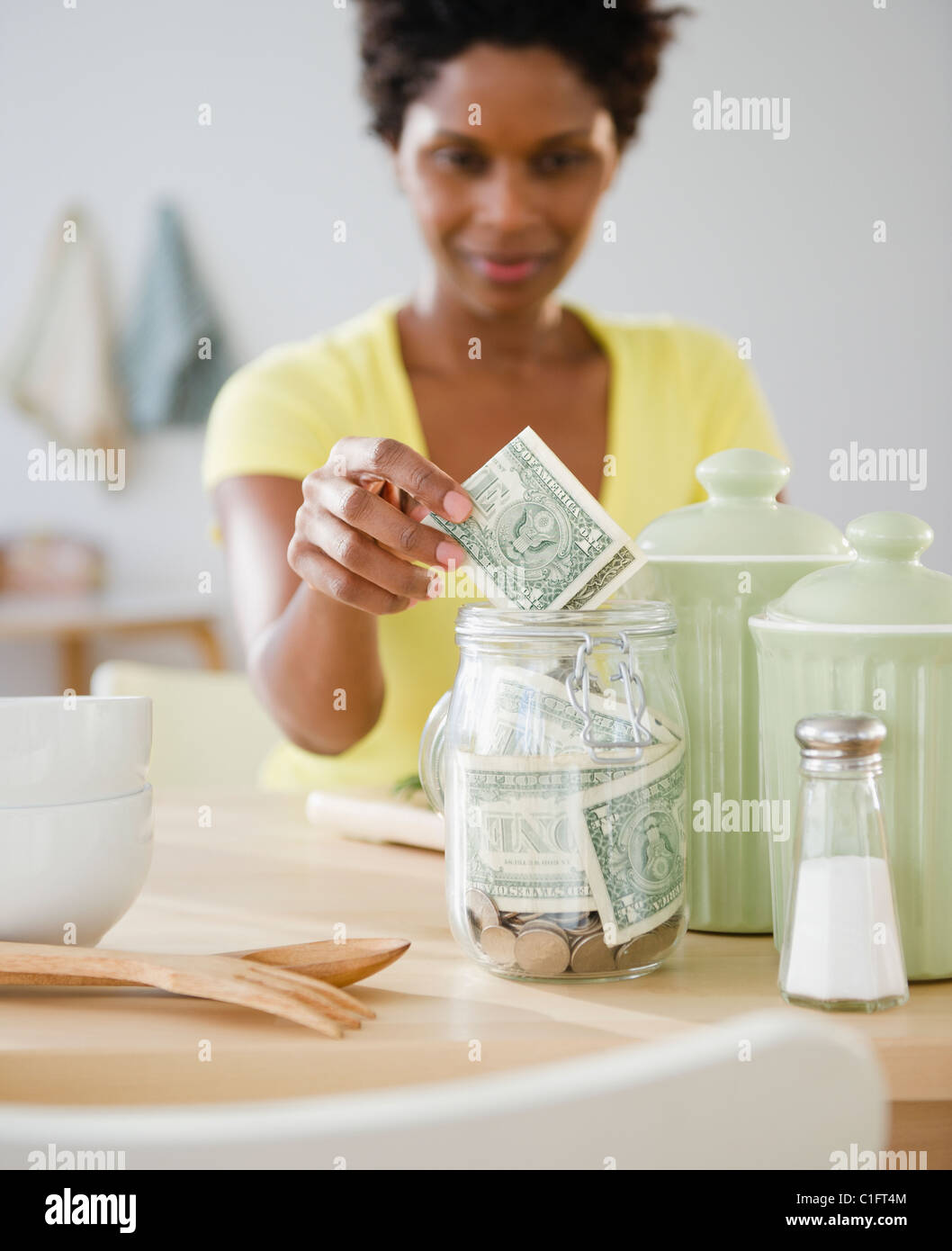 Black woman putting money in jar Stock Photo