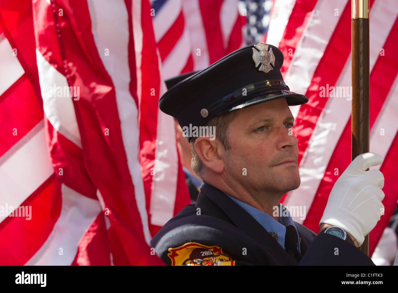 Firefighter from the 343 Honor Company honoring the firefighters who lost their lives on 9/11/2001 carrying an American flag Stock Photo