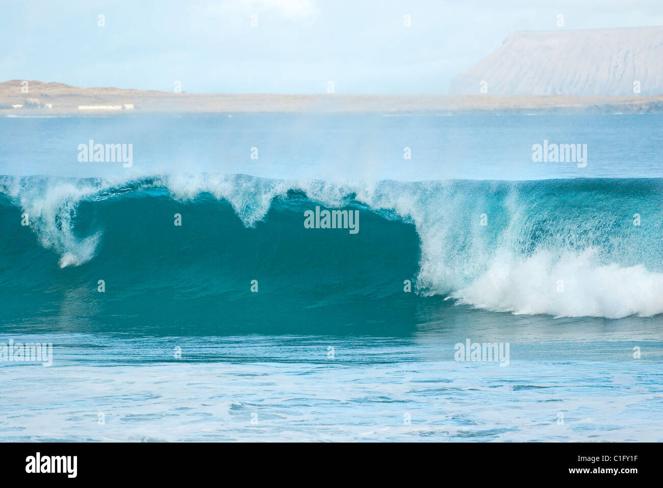 Graciosa Island beyond wave at Playa Canteria beach near the fishing village of Orzola at the NE tip of the island, Lanzarote Stock Photo