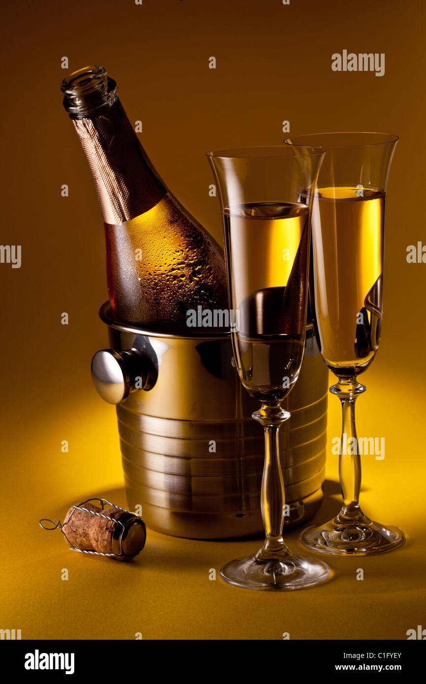 Champagne bottle in cooler and two champagne glasses. Isolated on a yellow. Stock Photo