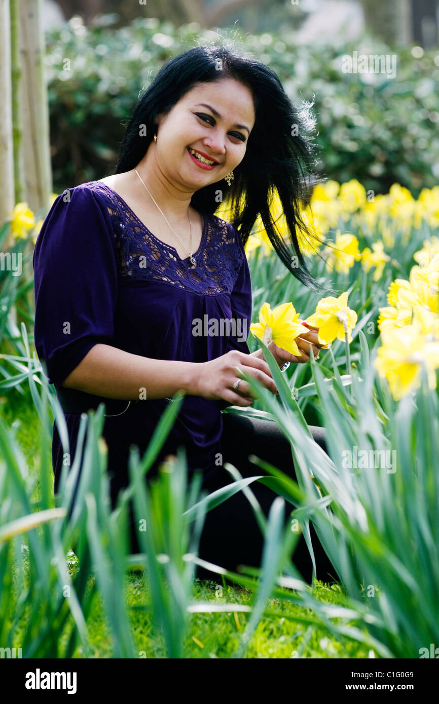 woman sitting in public park amongst spring daffodils Stock Photo