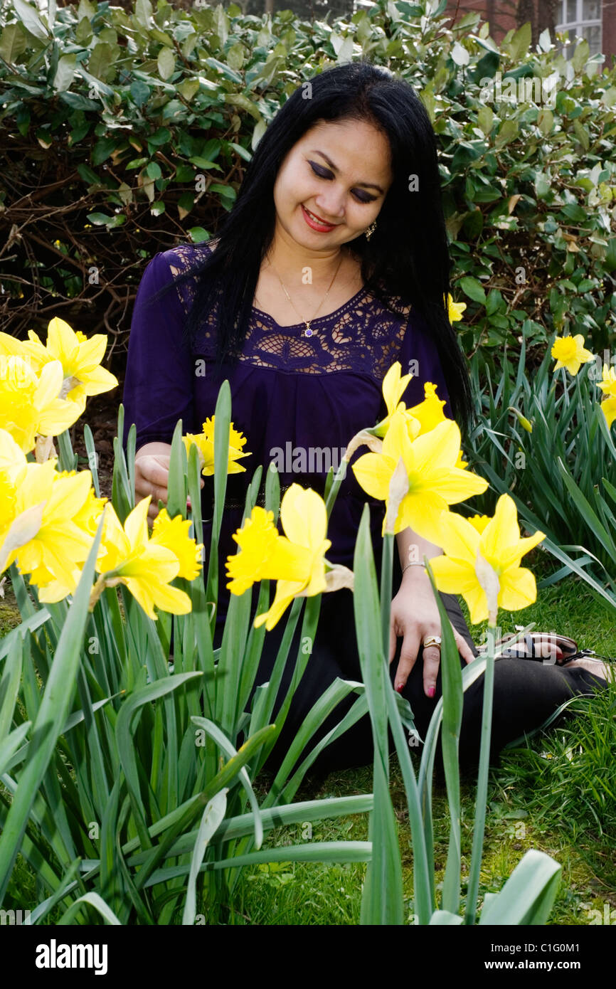 woman sitting in public park amongst spring daffodils Stock Photo