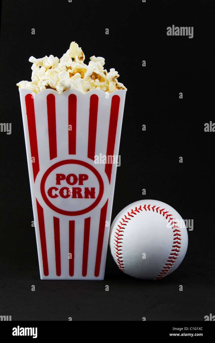 Baseball next to red and white container of fresh popcorn is a 