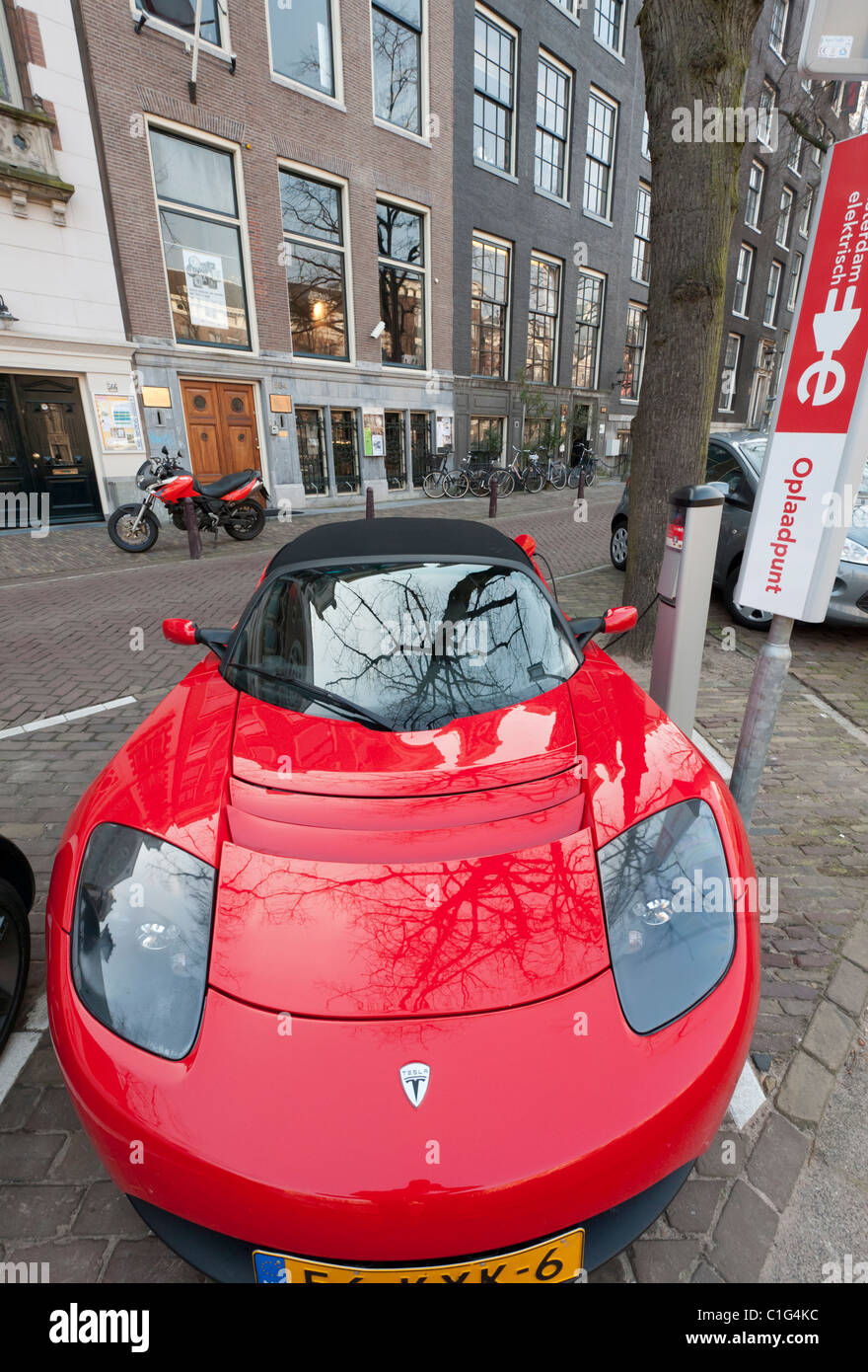 Electric Tesla sports car being charged at public recharging point in