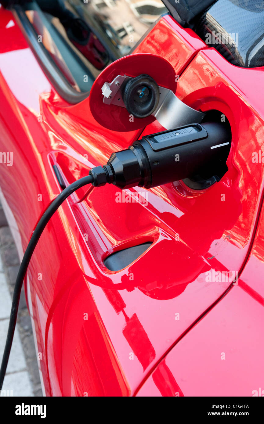 Electric Tesla sports car being recharged at public recharging point in