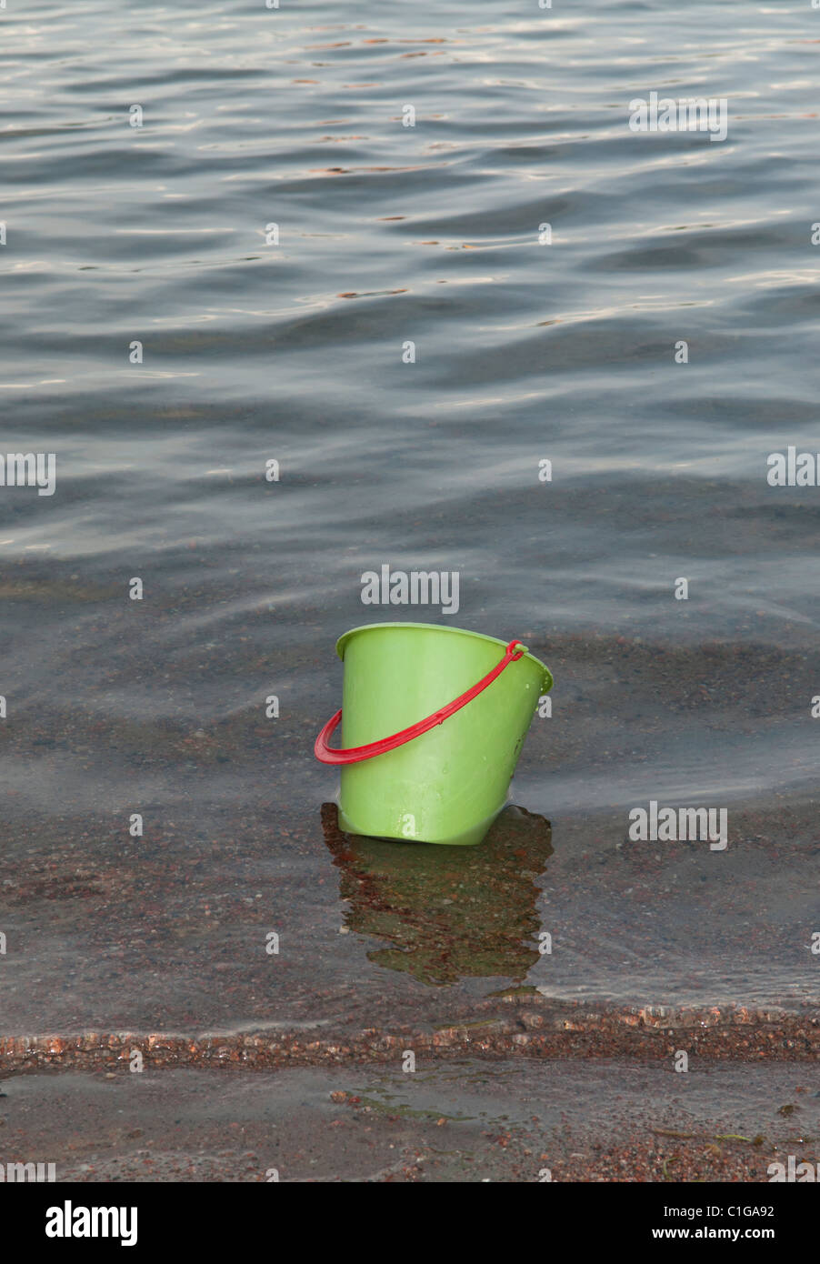Green children's playing bucket floating in the water, close to the
