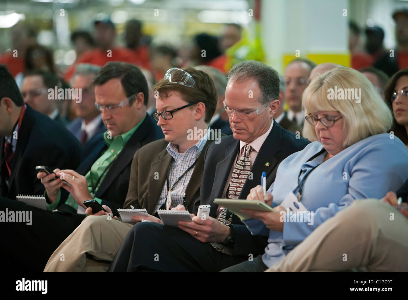 Reporters take notes during speeches by company and union officials at an event celebrating the launch of the 2012 Ford Focus Stock Photo